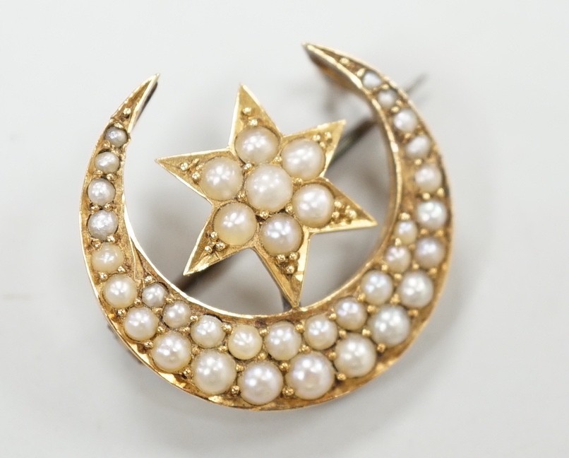 An Edwardian yellow metal and seed pearl set crescent moon and star brooch, 22mm, gross weight 4 grams.